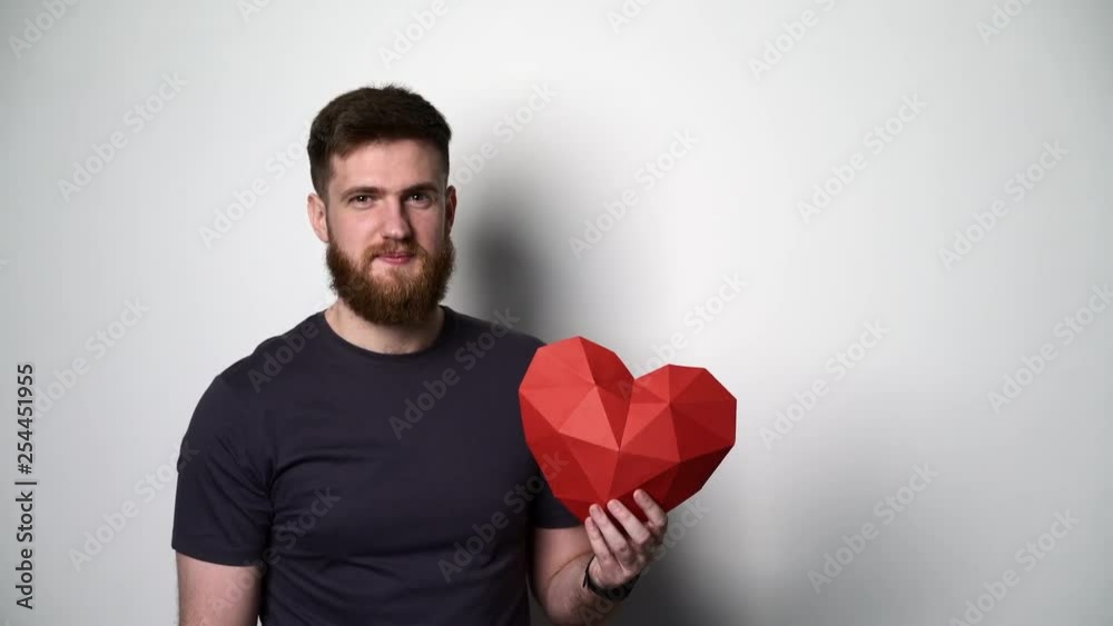 Half length portrait of young bearded hipster man holding red heart shape Half length portrait of young bearded hipster man holding red heart shape