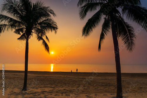 Silhouette palm tree, father and his son standing view at the sea during sunrise © Thapanon Phoonchai