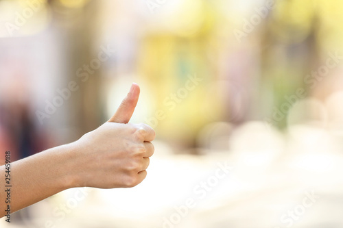 Female hand showing thumb up on blurred background
