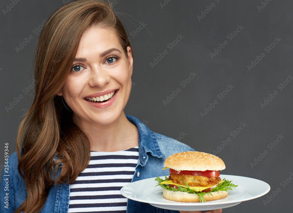 smiling woman holding burger on white plate