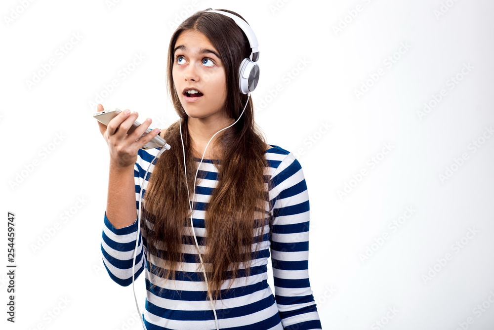 young beautiful girl speaks by mobile phone. Girl with headphones and mobile phone.  student talks to her friend. modern Teenager on a white background