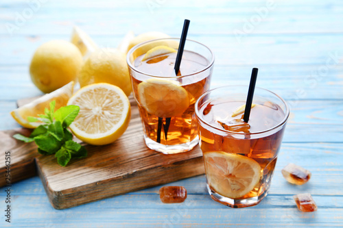 Ice tea in glasses with lemon and mint leafs on wooden table