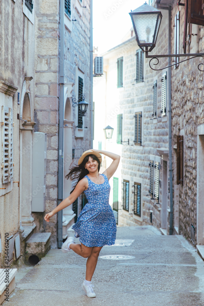 young pretty woman in blue dress walking by little streets of Herceg Novi