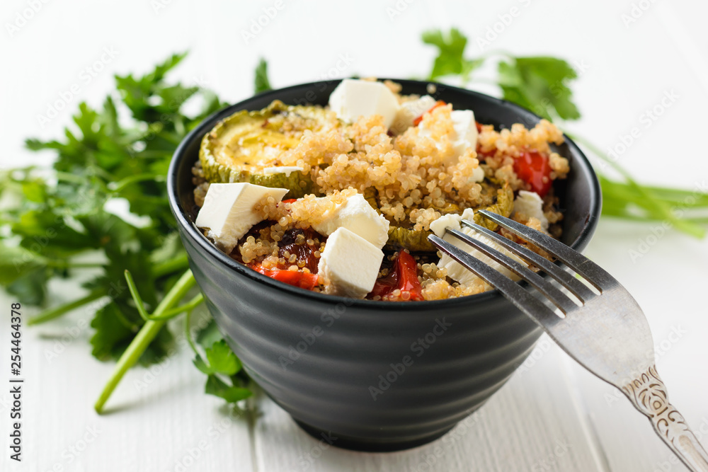 Baked vegetable salad with quinoa and Serbian cheese on a white table. Vegetarian dish.