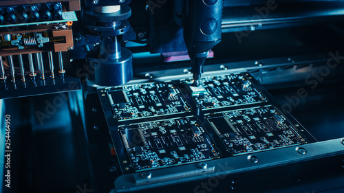 Factory Machinery at Work: Printed Circuit Board Being Assembled with Automated Robotic Arm, Surface Mounted Technology Connecting Microchips to the Motherboard. Macro Close-up. photo