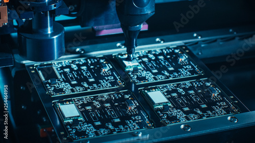 Macro Close-up Shot of Printed Circuit Board on a Factory Assembly Line with Automated Robotic Arm for Surface Mounting Microprocessors to the Motherboard.  photo
