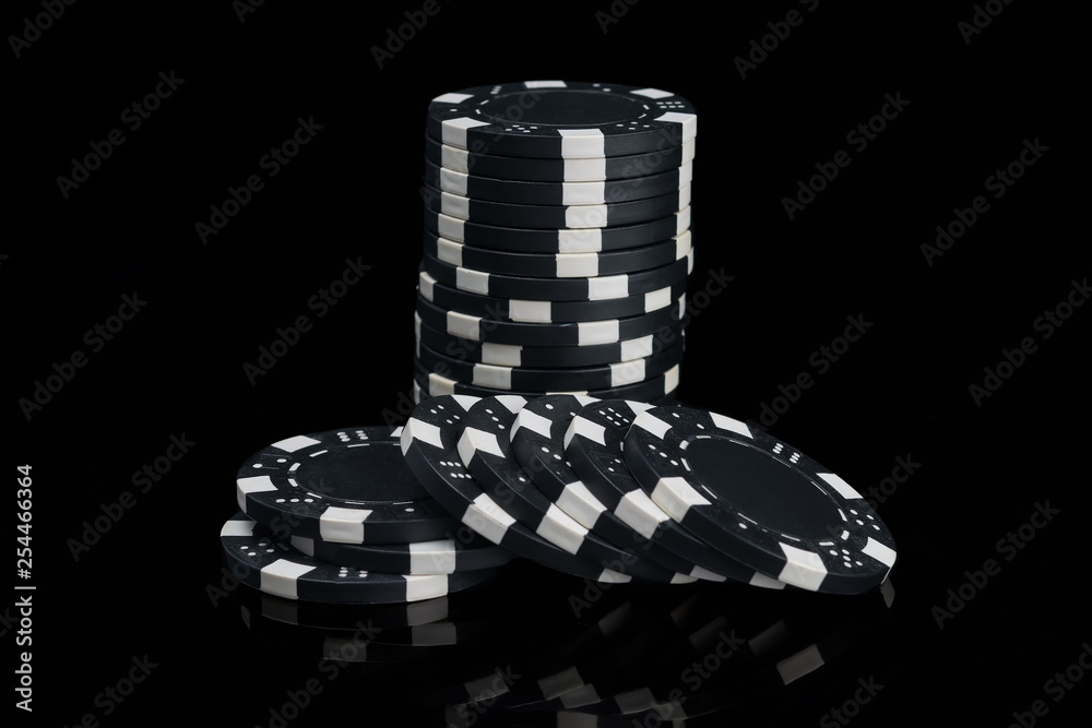 heap of black poker chips reflected in black background