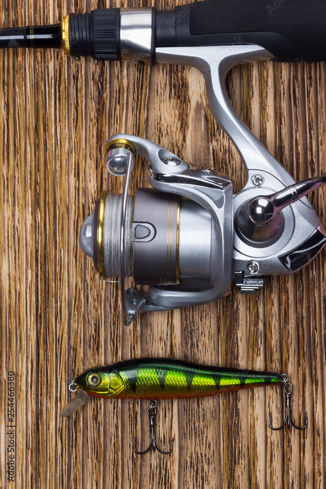 fishing rod with reel and tackle for fishing on the background of dark boards close-up fishing rod with reel and tackle for fishing on the background of dark boards close-up