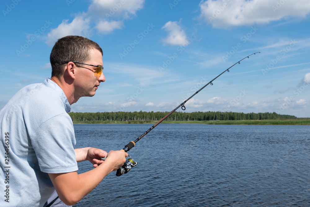side view, a man with glasses is fishing for spinning in open water side view, a man with glasses is fishing for spinning in open water