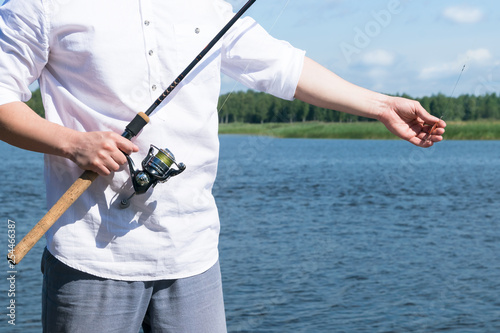 front view, a man holds a fishing rod for fishing close-up
