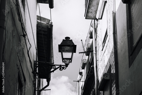old lamp in a narrow street in porto portugal - black and white