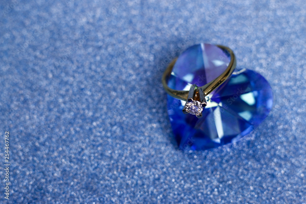 Golden engagement ring with gem of diamond fixed on the blue heart-shaped crystal. Golden engagement ring with gem of diamond fixed on the blue heart-shaped crystal.
