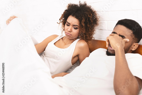 Woman in bed looking under blanket, man with erectile dysfunction photo