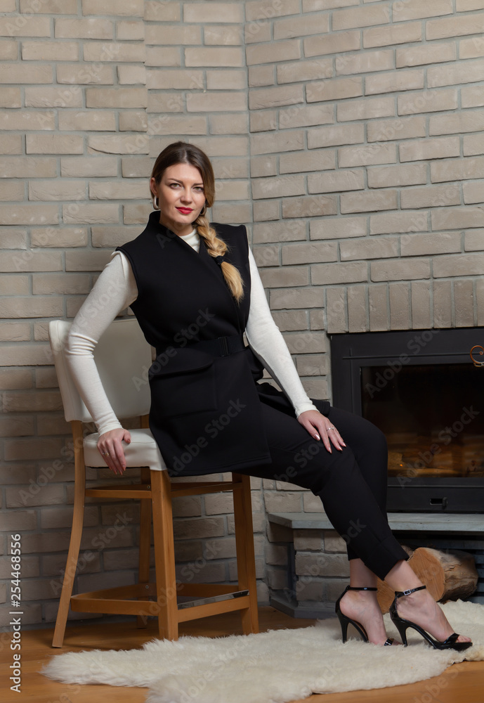 Fototapeta premium Blonde in a black vest and fireplace