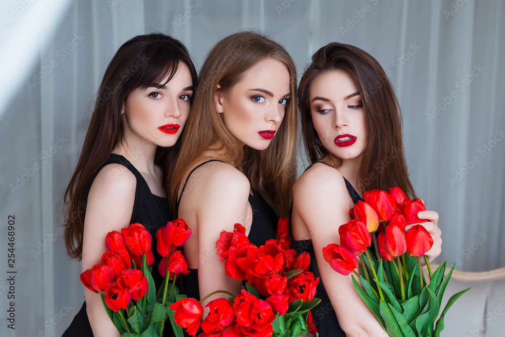 Fototapeta Modelki w delikatnych czarnych sukienkach pozują zmysłowo w luksusowym wnętrzu pełnym tulipanów. Zmysłowość młodej kobiety.