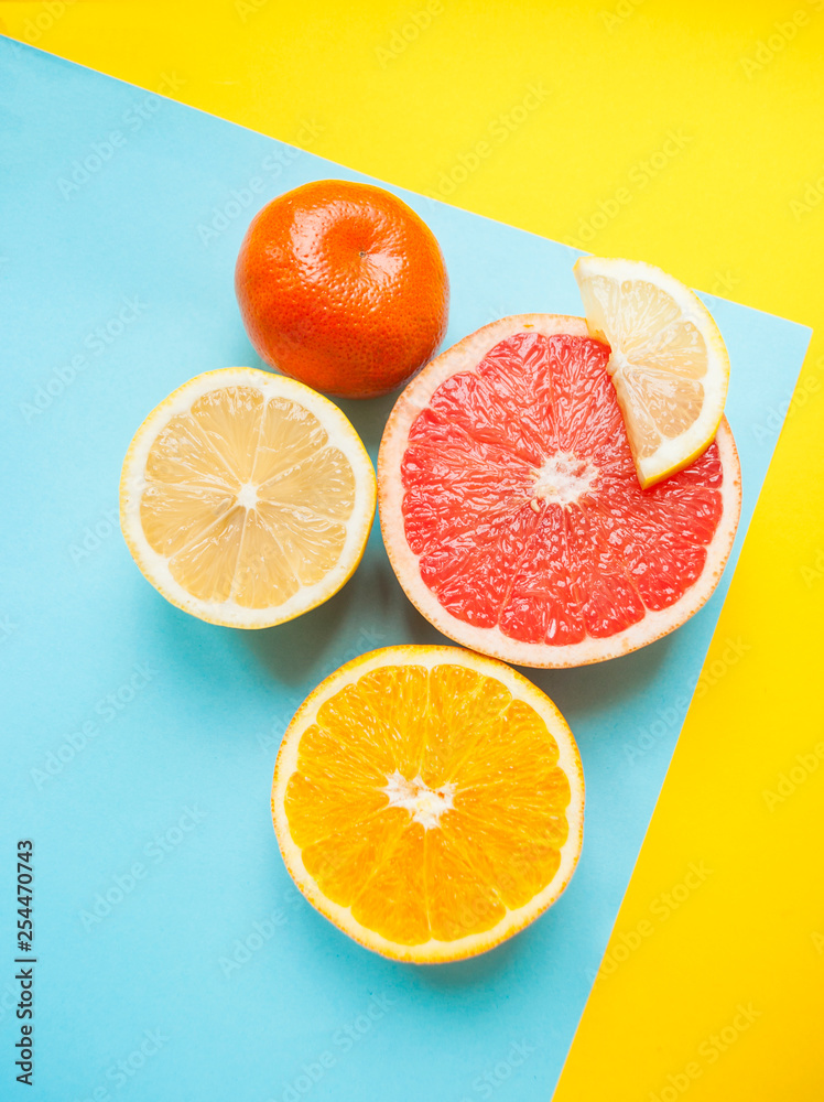 Flat lay of cut ripe juicy grapefruit, lemon and orange on yellow and blue background. Citrus pattern. Flat lay of cut ripe juicy grapefruit, lemon and orange on yellow and blue background. Citrus pattern.