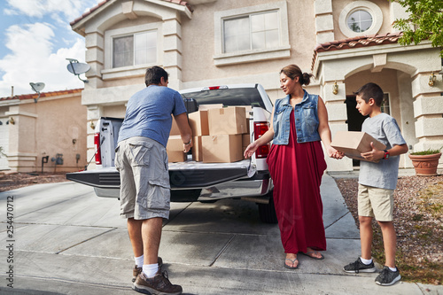 Photography hispanic family unloading pickup truck and moving into new house in las vegas