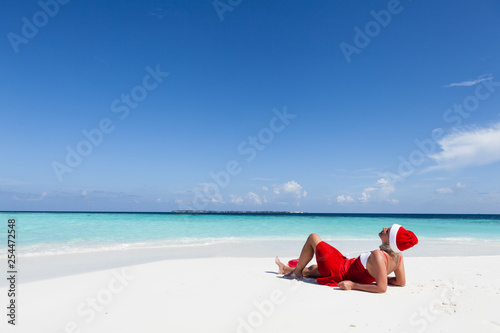 Santa Claus woman relaxing on the beach