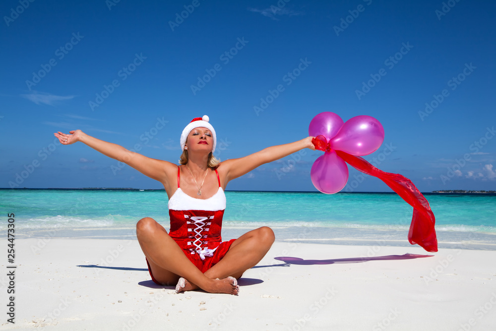 © Avatar_023 - Beautiful woman in Santa Claus costume sitting on the beach