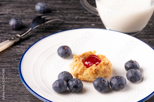 Shortbread cookies made of walnut dough with strawberry jam on a plate with blueberries and a fork.