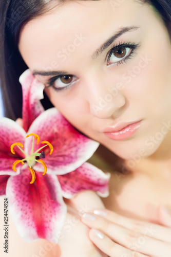 Close-up, beauty portrait of a young, beautiful Caucasian woman holding lily flower. Shallow depth of field