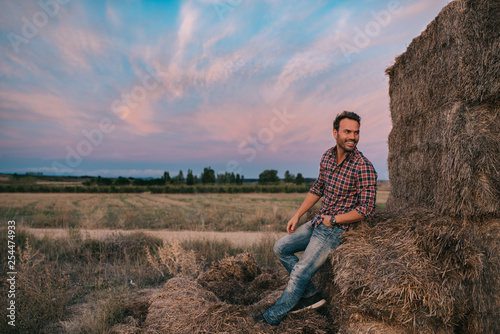 Happy man sitting on a pile of hay