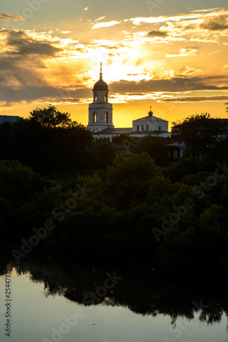 landscape of mirror river and small russian church with amazing sunset on background in village area. © Антон Паршунас