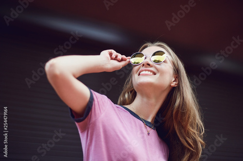 Blond girl in sunglasses smiling on a striped  background.