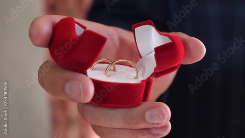 bridegroom holds in his hand box of gold wedding rings, close-up. gift golden decoration. jewelry for his beloved woman