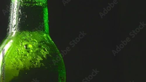 cold beer in a green bottle with water drops on a dark background. 4K UHD video 3840x2160