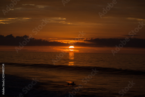 Sunset reflecting in the ocean behind clouds 