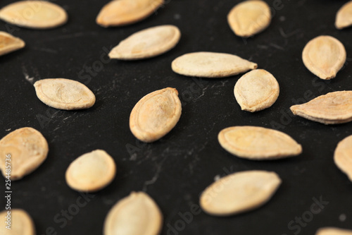 Roasted and salted pumpkin seeds on black board, shallow depth of field photo