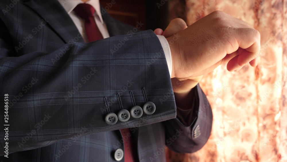 man button up his buttons on his jacket, close-up. businessman puts on a blue jacket in a cage. office worker gets dressed in the morning. concept of stylish and fashionable clothes for men