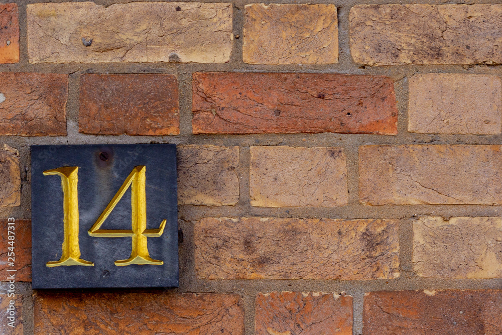 fourteen written in gold lettering on a black slate on a red brick wall fourteen written in gold lettering on a black slate on a red brick wall