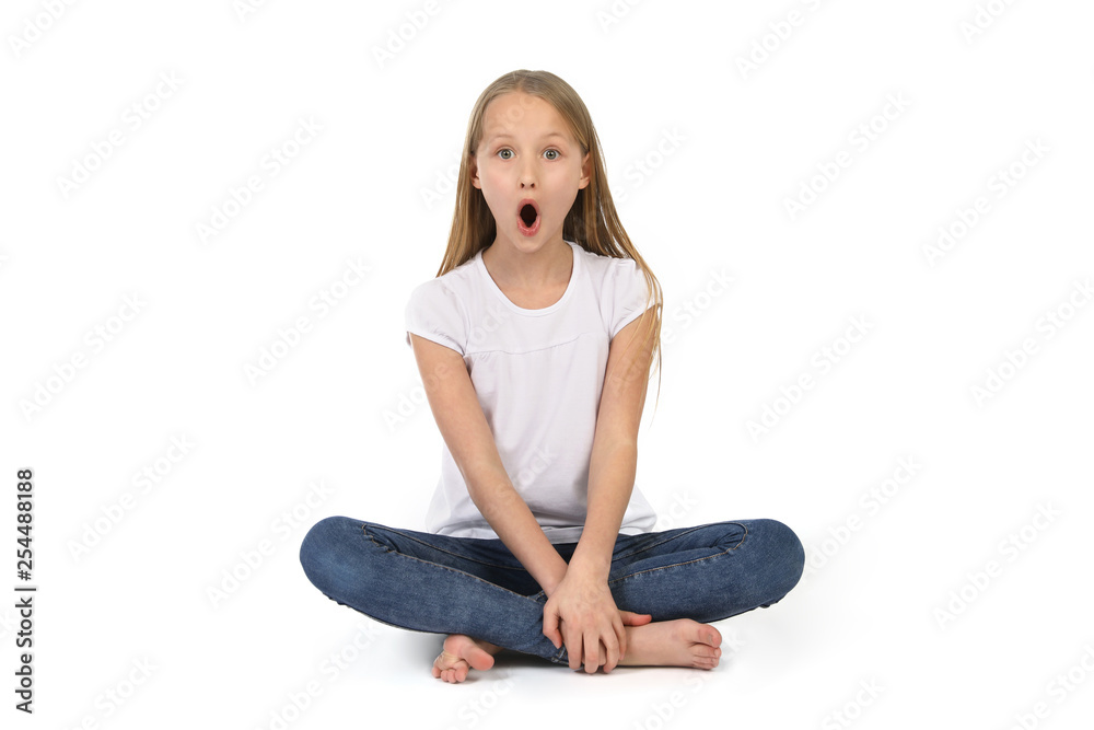 Junges Mädchen sitzt auf dem Boden und schaut erstaunt Junges Mädchen sitzt auf dem Boden und schaut erstaunt