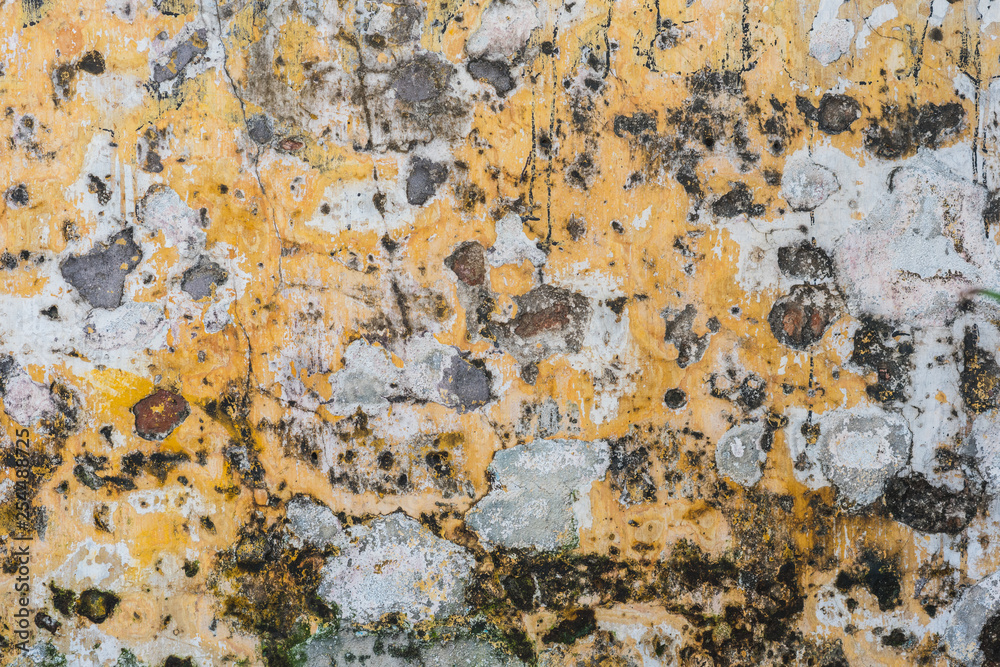Weathered and scratched old yellow wall. Typical texture of an old wall of the ancient yellow city of Hoi An, Vietnam.
