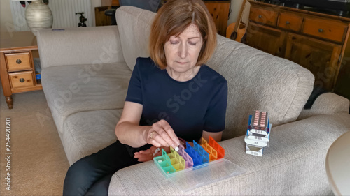 Photos Retired woman organising her pills for the week at home