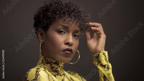 mixed race african american woman in bright yellow dress with python print. 90's style touches her natural curly short hair and smiling to the camera photo