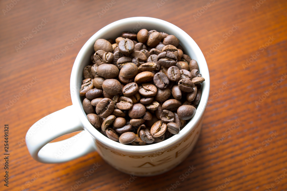 coffee beans in white mug on wooden background coffee beans in white mug on wooden background