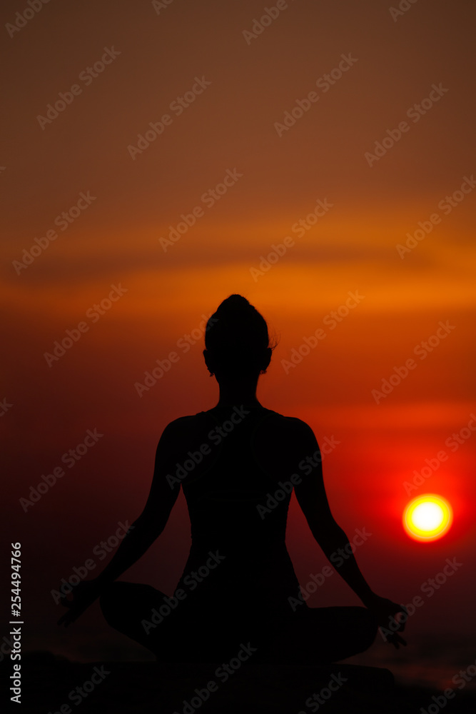 Yoga near the sea at sunset. Meditation and relaxation. Siluet.