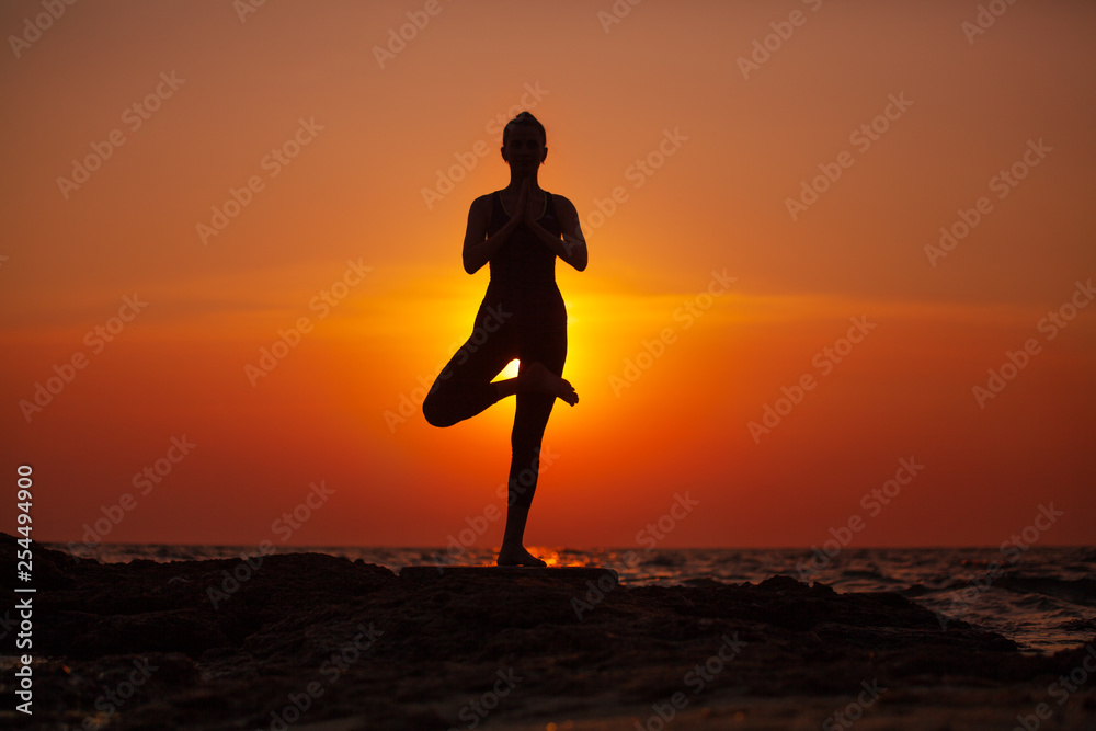 Yoga near the sea at sunset. Meditation and relaxation. Siluet.