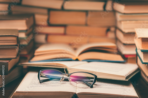 Open book and glasses on wood desk in the library room with narrow depth of field for education background and back to school concept