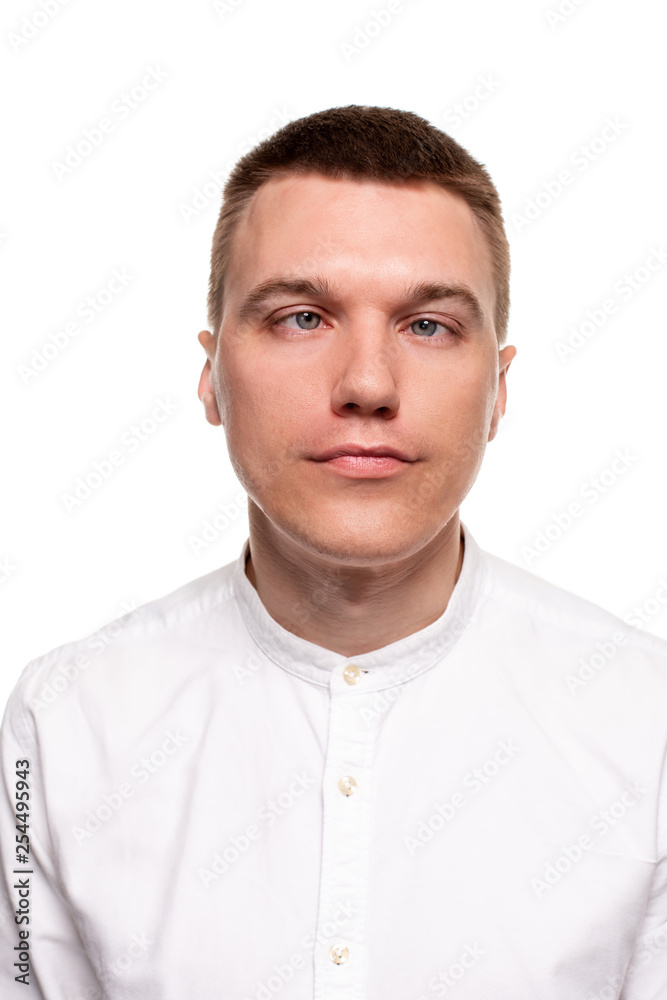 Charming handsome young man in a white shirt is making faces, while standing isolated on a white background Charming handsome young man in a white shirt is making faces, while standing isolated on a white background