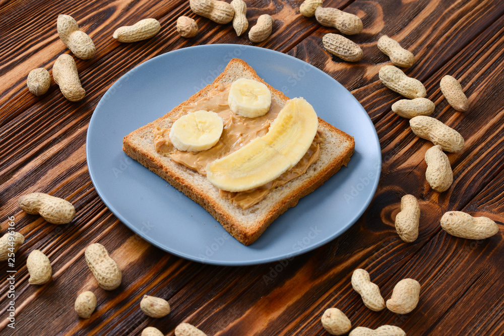 Peanut butter toast with banana slices on wooden background Peanut butter toast with banana slices on wooden background