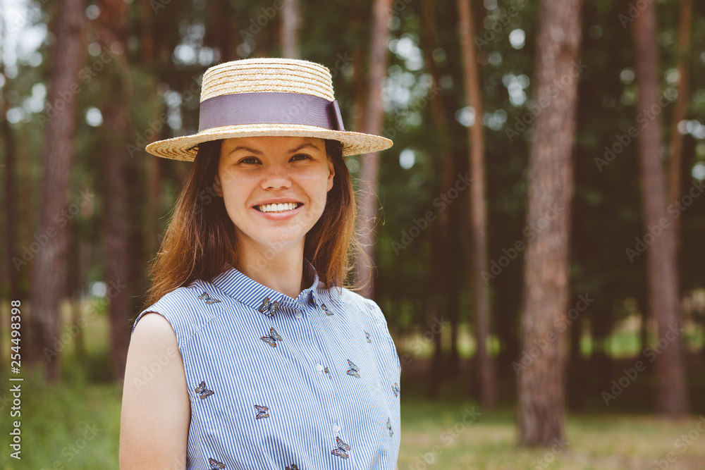 Joyful woman in straw boater hat smile on nature in summer