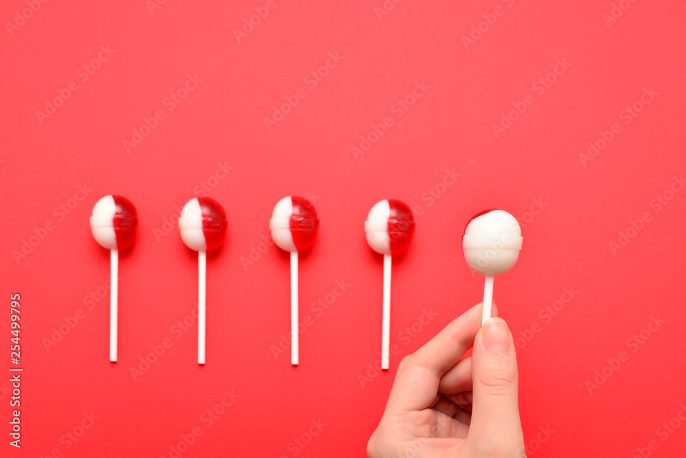 Lollipop in female hand on red background. Space for text or design. Lollipop in female hand on red background. Space for text or design.