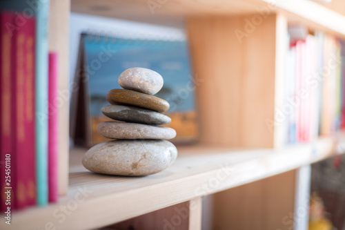 Feng Shui: Stone cairn in a book shelf in the living room, balance and relaxation. Sunlight.
