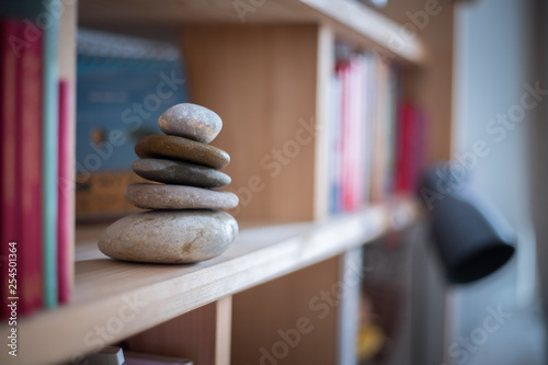 Feng Shui: Stone cairn in a book shelf in the living room, balance and relaxation