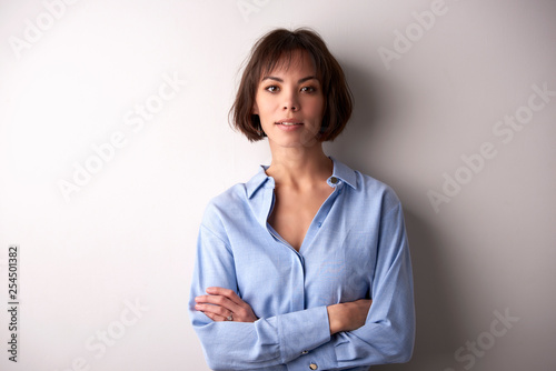 Schilderij op canvas Attractive businesswoman with folded arms standing at isolated background