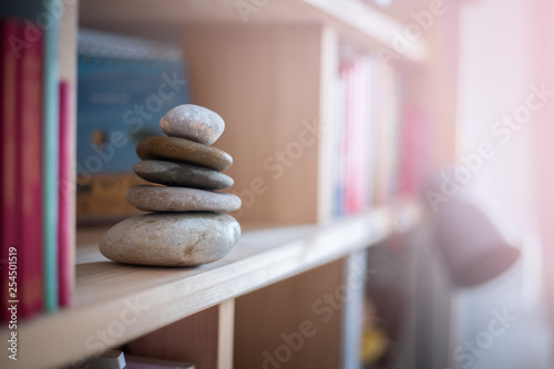 Feng Shui: Stone cairn in a book shelf in the living room, balance and relaxation. Sunlight.